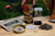 Shows the interior items of the case. A clear cylinder, small amount of dirt and white stones, seeds, and instruction kit are displayed.