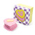 The heart shaped candle displayed next to its square packaging.