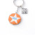 One side of the New Glory penny keychain, white star on an orange background, txt says USA, on a silver keyring.
