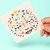 A hand holding the face sticker sheet. A hand holding the face sticker sheet.