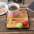 three dinosaur shaped tea infusers on a wooden cutting board, one in a cup of tea
