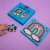 the contents of the rainbow pom pom kit displayed next to a hand touching the colorful pom poms.