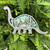 A wooden brontosaurus standee features a layered 3-d center in which a forest scene and two other brontosaurus can be seen. Teal colors are featured in the background.
