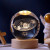 A crystal sphere lamp with the solar system engraved in the interior on a wooden USB powered base.
