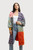 A woman wearing the multi-patterned cardigan. It falls to just below her knees and features several blocks of color patterns, including purple with black flowers, zebra stripes, red with orange geometric shapes, pale blue with gold organic shapes, and white with red repeating pattern.