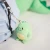 Keychain, green dinosaur plush toy. Photographed hanging from a backpack zipper.