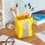 Yellow pen holder that is shaped like a giant pencil sharpener. Photographed holding pencils and sitting on a desk.