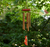 Picture of windchime hanging. Warm cord connects bronze colored tubes to a central hook, while a painted cardinal acts as the wind sail. The wooden top of the windchime is red like the cardinal.
