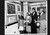 Black and white photo, a crowd looking at art.