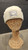 A photo of the bone beanie. The knit texture is visible. Centered on the cuff is a silver patch bearing the CMNH Logo  on a mannequin. This includes text reading "CMNH" and "Established 1895" above and flanking the silhouette of Dippy, the CMNH logo, in bone. "Carnegie Museum of Natural History" is written below this.