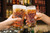 Two full pint beer glasses etched with a Pittsburgh street map being used in a toast