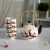 A photograph of the tea set. The tea pot is a traditional shape, with a top lid and detachable bamboo handle. It has a white base, black spout, and black accents on the ball atop its lid. Both the tea pot and tea cups are white, decorated with a cherry blossom branch -- the branch is black, with red and pink blossoms.