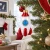 A blown-glass ornament in the shape of a retro-style rocket hanging from a Christmas tree