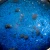 A detail image of a pendant with lunar dust contained in glass against a blue background