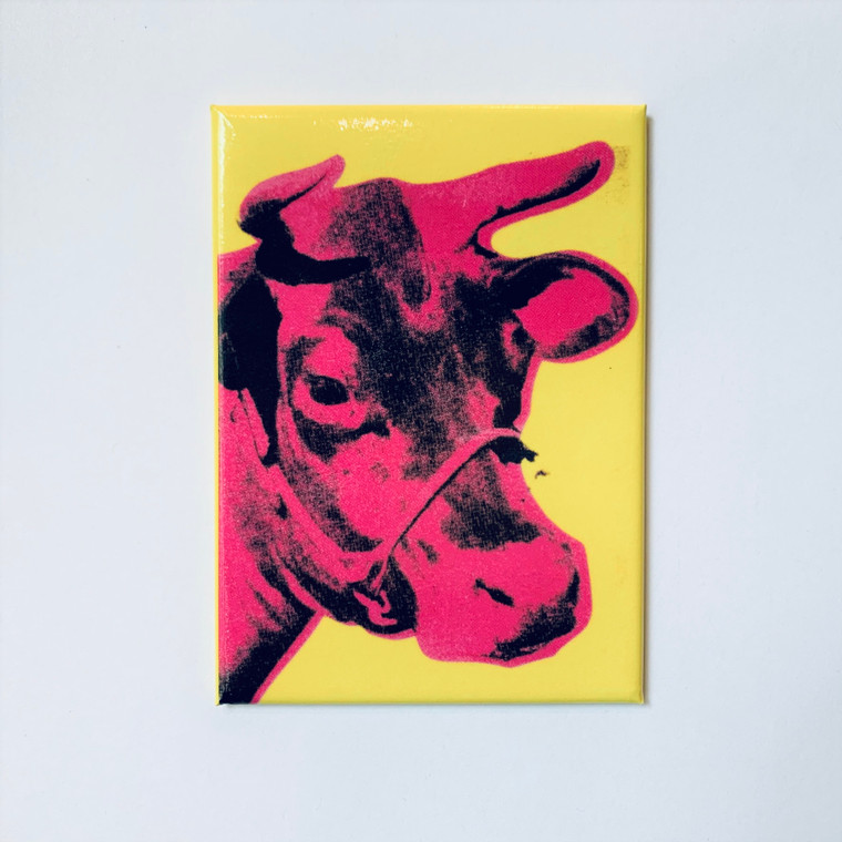 A rectangular magnet with a pink cow on a yellow background.