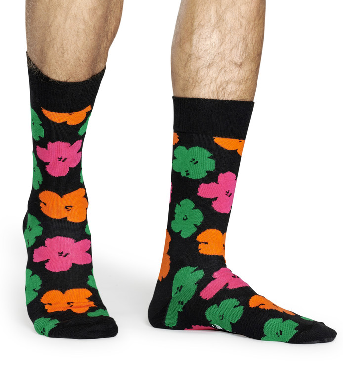 Legs of someone wearing black socks with multicolor flowers.