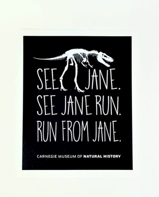 Sticker Black base with white T-rex skeleton and text.

SEE JANE . SEE JANE RUN. RUN FROM JANE.
Size 4" W x 4.5" T