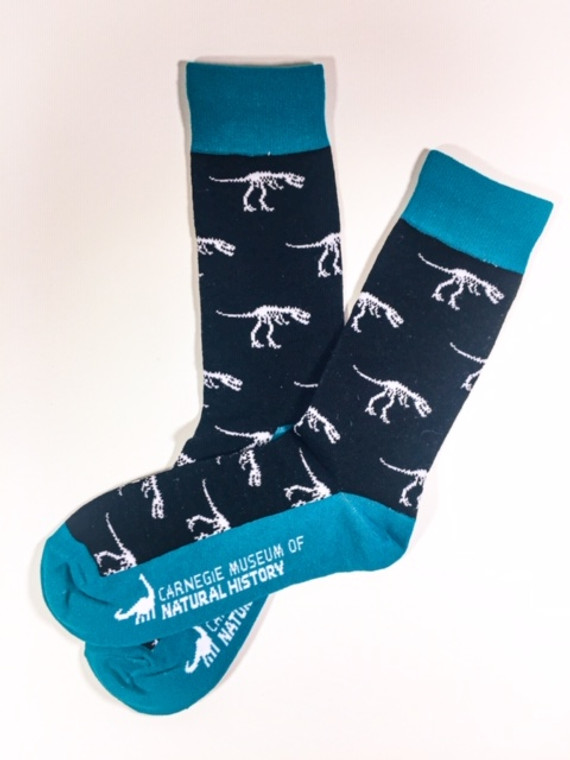 Crew sock cotton nylon blend, teal band and heel, black body with white T-Rex skeletons.  Carnegie Natural History logo on bottom of sock.
