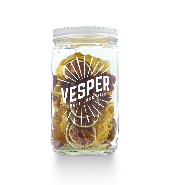 clear glass jar with dried pineapple, cranberries and limes inside