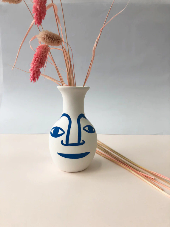 white vase with a line drawn blue face.