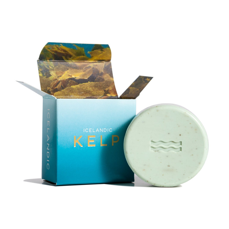 open box with soap next to it, box features a blue gradient with an image of kelp on the inside, the soap itself is round and a pale teal color