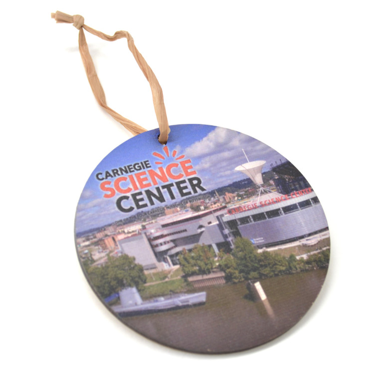 A round wooden ornament with a riverside view of the Carnegie Science Center.