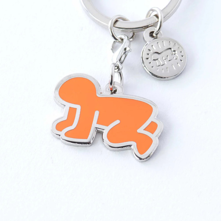 Orange radiant baby artwork enamel keychain with additional charm.
