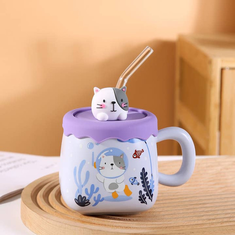a ceramic mug featuring a cat in a diver suit underwater, the lid is silicone with a cat had on it and a glass straw