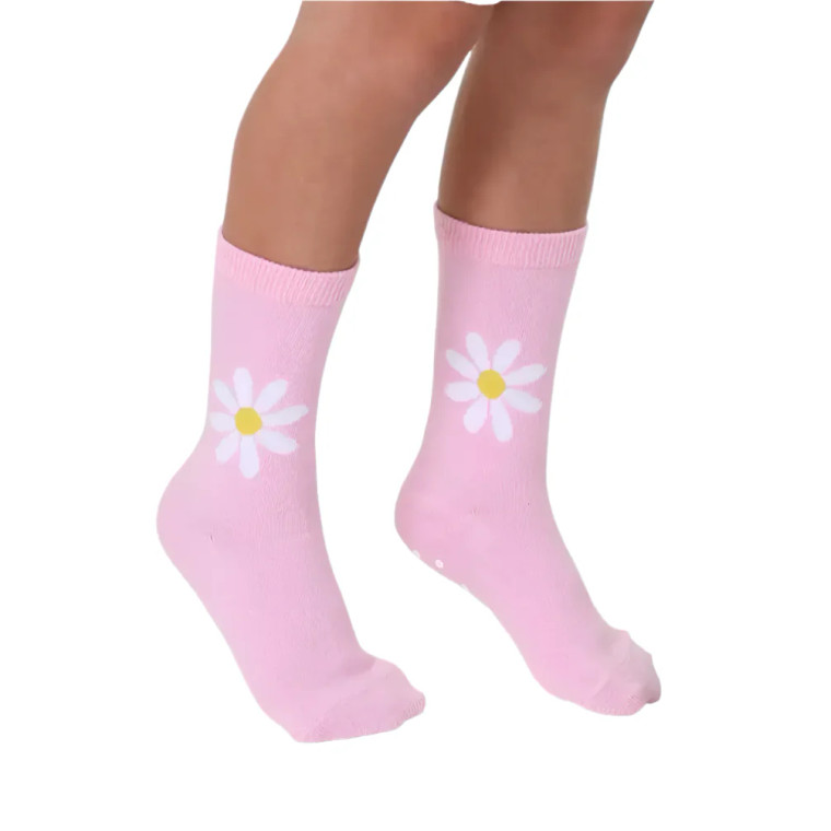 A child wearing a pair of pink crew socks with white daisies just above the ankle