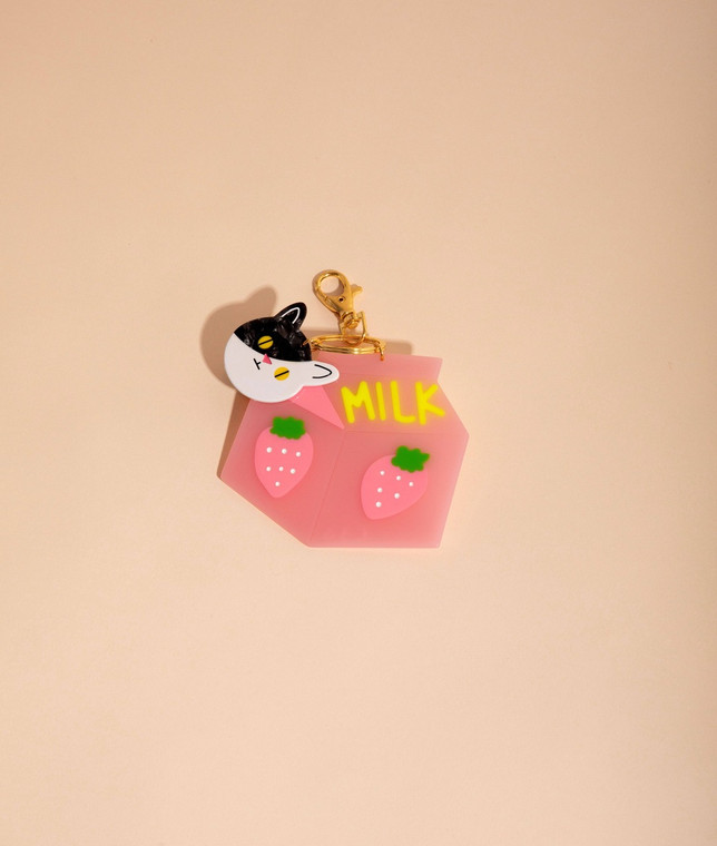 Pink flat shaped milk carton keychain with a small flat black and white cat head.