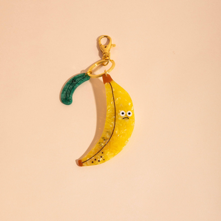 Banana shaped flat charm attached to key ring and a smaller pickle shaped charm.