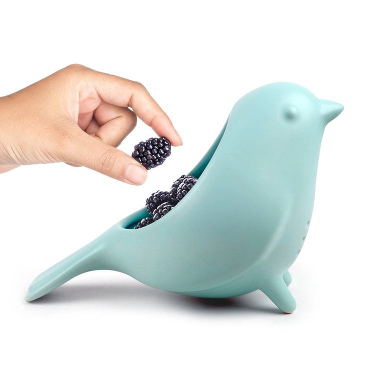 person's hand reaching blue bird ceramic colander holding blackberries