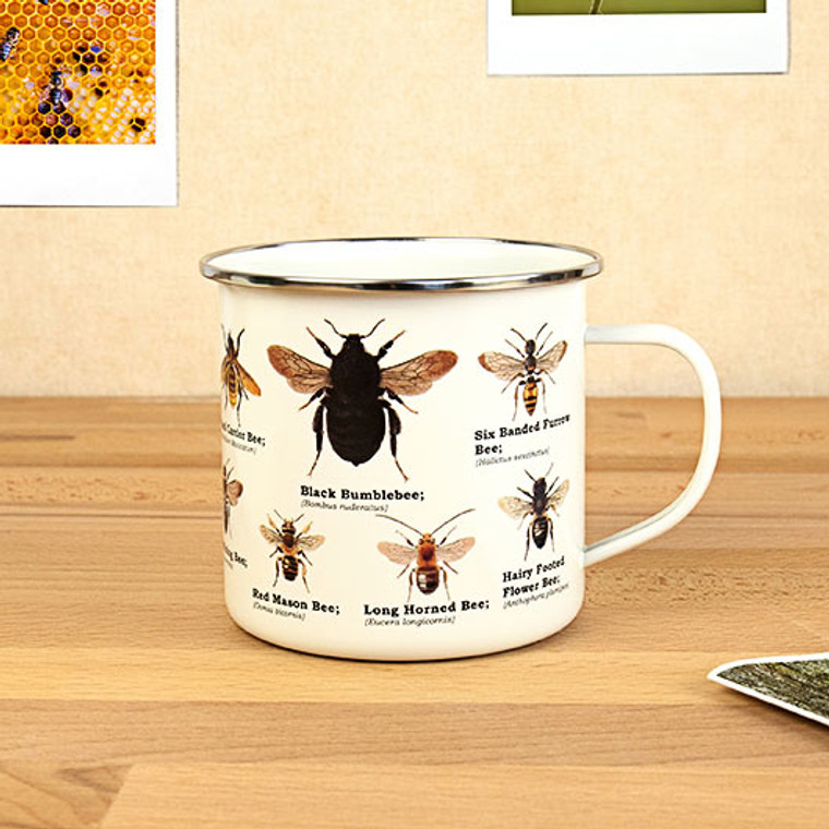 white metal mug with bees printed on it in front of a beige background