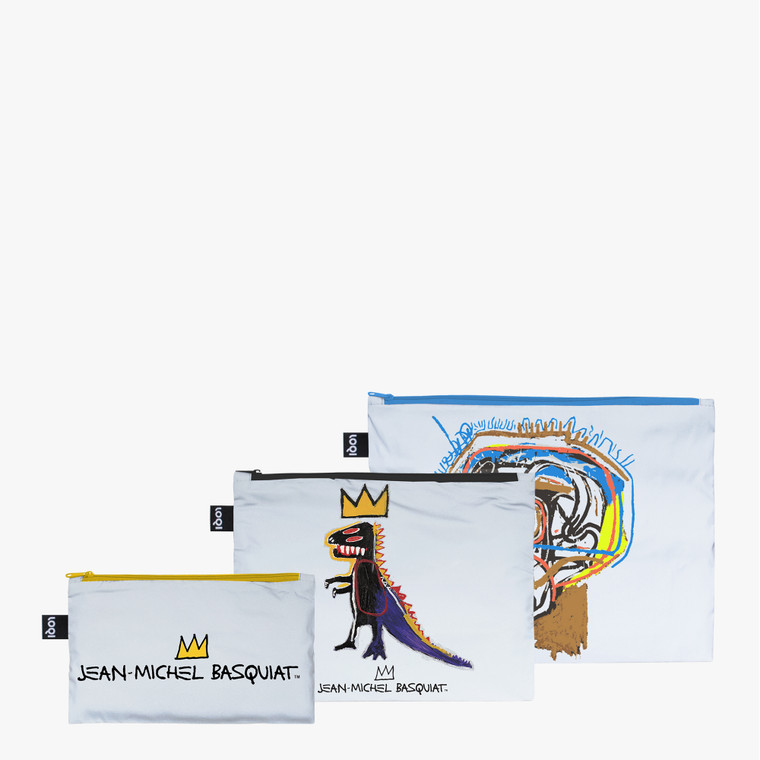 set of three reflective zippered rectangular bags, in three different sizes. Each has an image of Basquiat's art work.