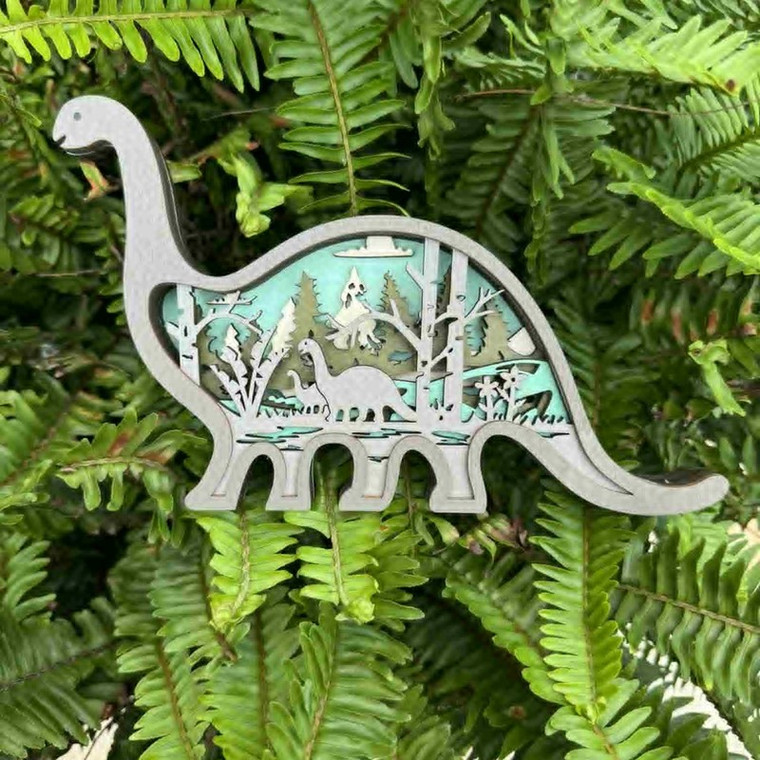 A wooden brontosaurus standee features a layered 3-d center in which a forest scene and two other brontosaurus can be seen. Teal colors are featured in the background.