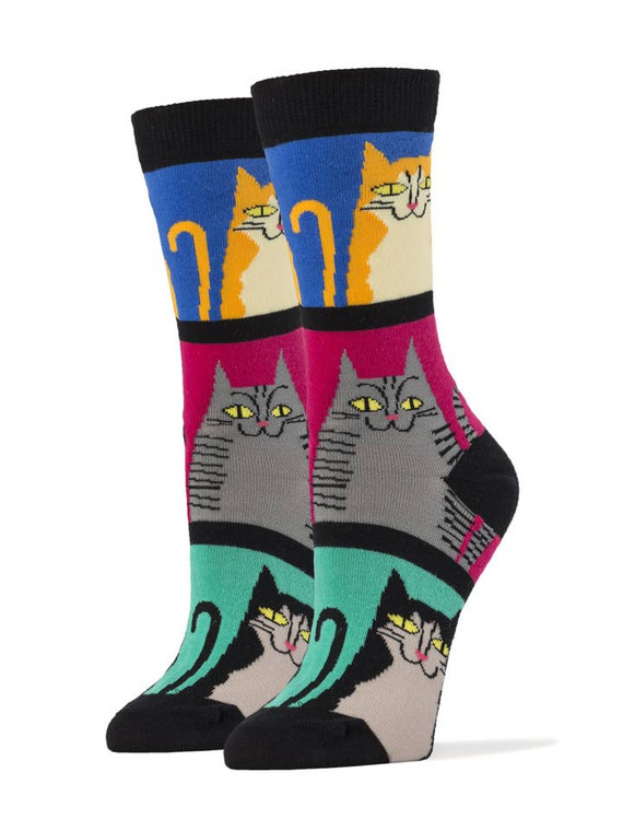 An image of the socks. Split into three distinct areas divided by bold black lines, modern art styled cats smile out. The top cat is orange in front of a blue background. The middle cat is gray with black stripes in front of a hot pink background. The bottom cat is a black and white tuxedo, in front of a bright teal background.