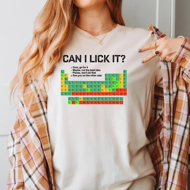 A woman wearing a beige t-shirt with a color coded Periodic Table of Elements