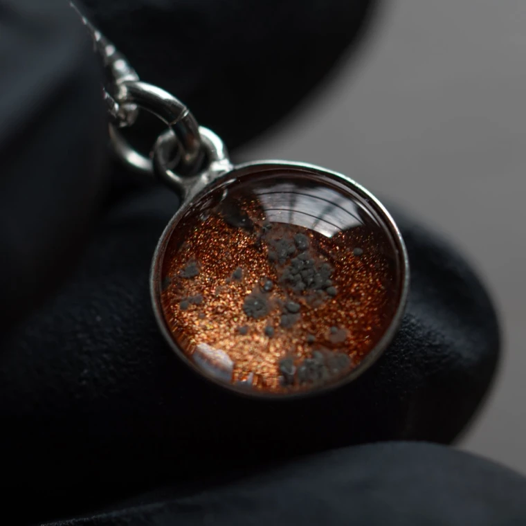 A pendant with martian meteor dust contained in glass against a red background