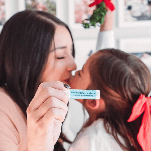 Mom and child kissing with customized happy holidays chapsticks. Mom and child kissing with customized happy holidays chapsticks.