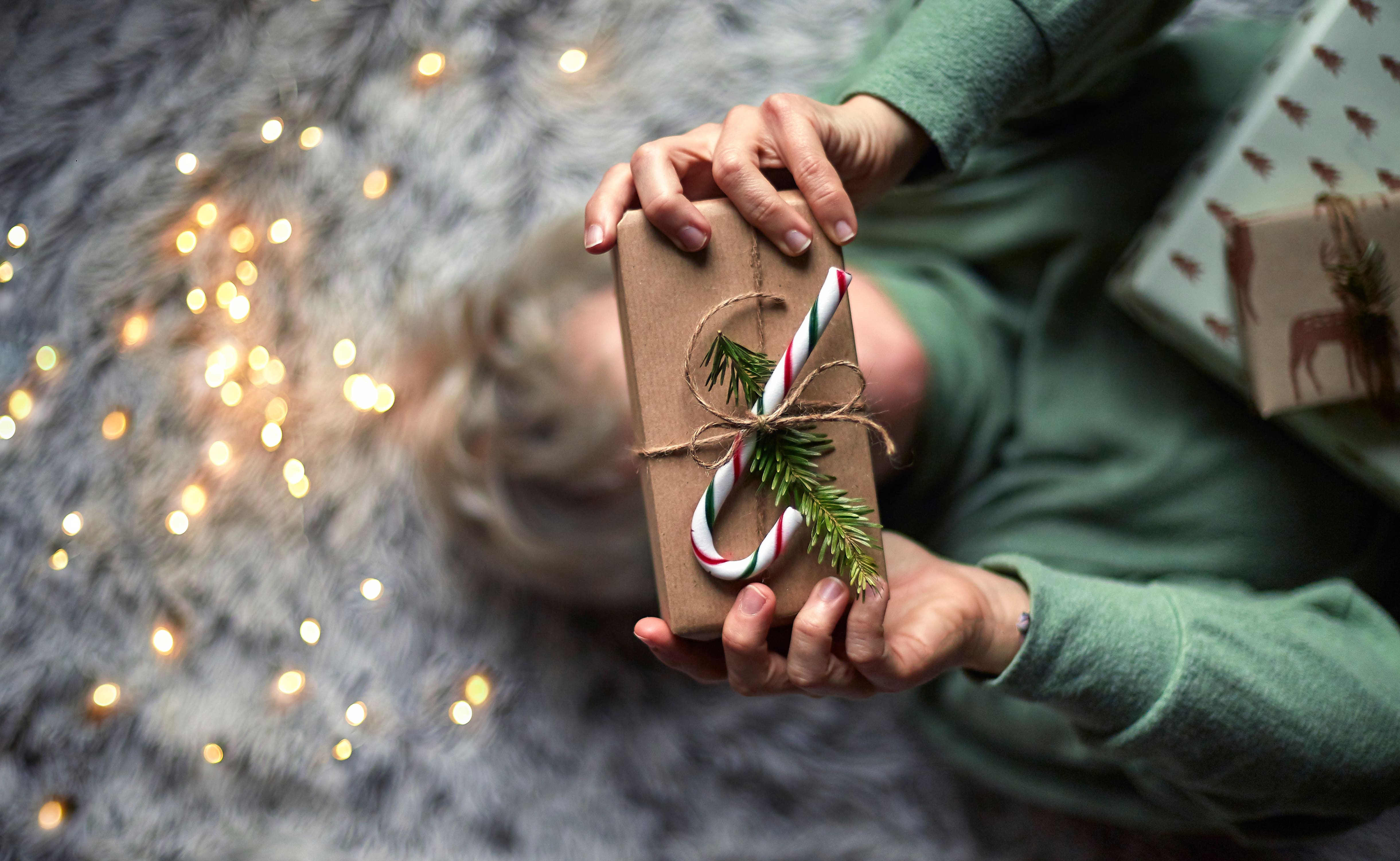 Person holding a wrapped gift with a candy cane