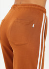 THE UPSIDE women's brown Zahara Roma Ankle Zip Pant is in a light slinky fabric. The high waisted pant features an invisible zip at the hem to be worn open or closed, an elasticated waist with a drawstring for adjustment and practical pockets at the front and back. These pants are designed for leisure and recovery.