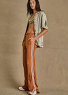 THE UPSIDE women's brown Zahara Roma Ankle Zip Pant is in a light slinky fabric. The high waisted pant features an invisible zip at the hem to be worn open or closed, an elasticated waist with a drawstring for adjustment and practical pockets at the front and back. These pants are designed for leisure and recovery.