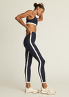 THE UPSIDE women's navy Hamptons 25 inch Midi Pant is made from recycled soft peached fabrication with a brushed handfeel and a breathable, quick drying effect. The high waisted pant has a V panel waistband and features colours of cream and white for an elevated look. Designed for yoga and pilates.