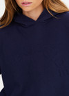 THE UPSIDE women's navy organic cotton Byron Embossed Logo Hoodie is designed for a relaxed boxy fit and features a tonal embossed horseshoe logo on the chest.