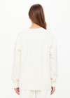 THE UPSIDE women’s creme cotton Hamsa Sunday Long Sleeve features a relaxed fit, dropped shoulders, and an embroidered evil eye on the sleeve. Perfect for layering.