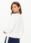 THE UPSIDE women's cream Jolie Isabeli Knit Cardigan is a regular fit with a blouson sleeve crafted from a pointelle knit and features navy embroidered bows. Made for tennis, golf & pickleball.