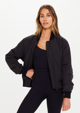 THE UPSIDE Kita Bomber Jacket in Black is sustainable classic bomber jacket with pockets, zip front closure, recycled insulation, and PCR free water repellent coating.