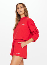 THE UPSIDE Courtsport Sabine Top in Chilli Red is a sustainable organic cotton cropped long sleeve top with ribbed mock neck, printed THE UPSIDE SPORT college logo in white and drop shoulders.