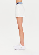 THE UPSIDE Bounce Palmer Short in White is a sustainable organic cotton high waisted short with contrast stripe ribbed waistband, pockets and fly front zipper opening and double button closure.