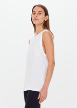 THE UPSIDE women's white Jeet Muscle Tank in organic cotton jersey is a relaxed fit tank with folded detailing and a printed tonal horeshoe logo.